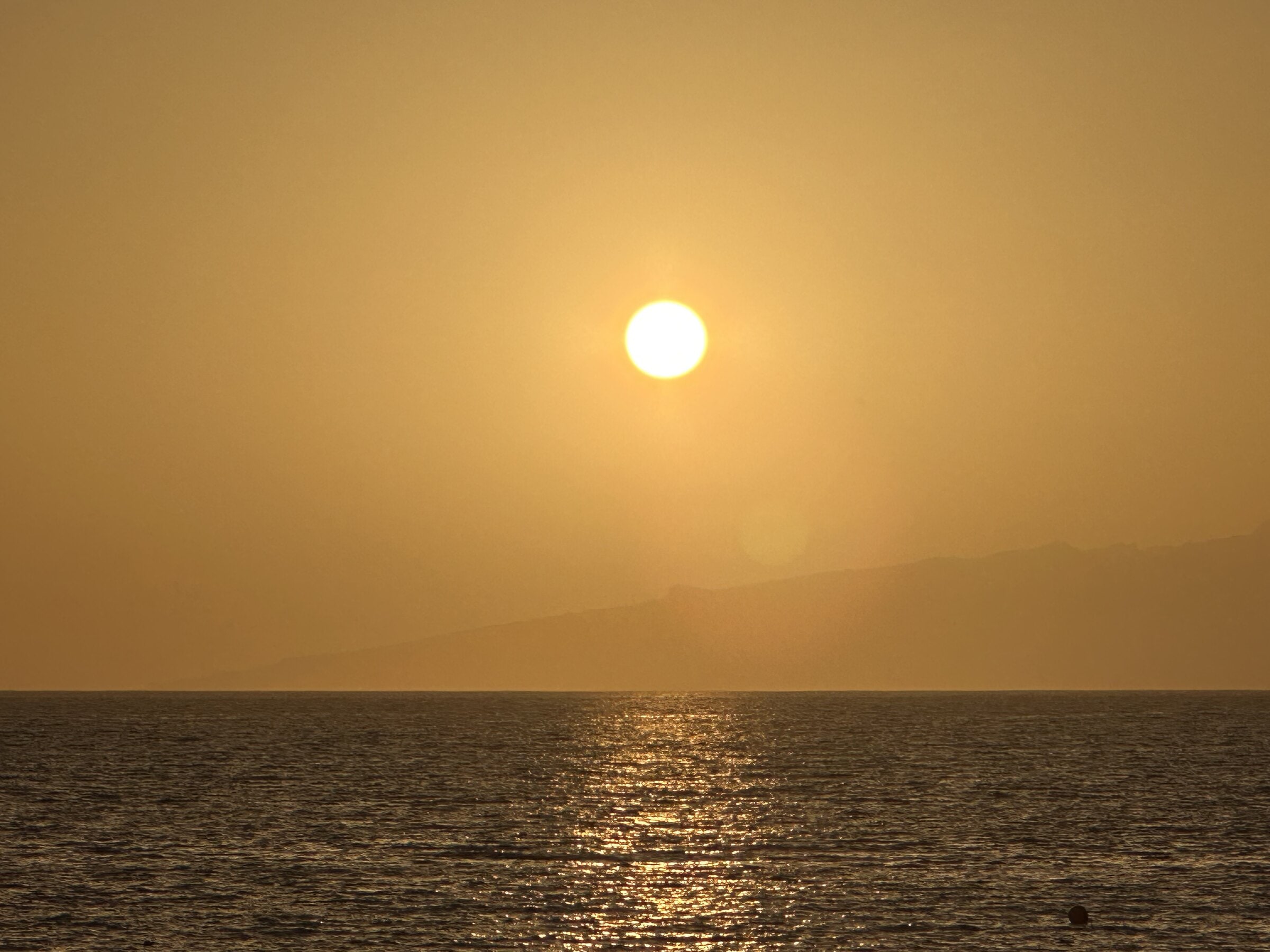 Puesta de sol desde la Playa de Torviscas, con el reflejo dorado sobre el mar y la silueta de La Gomera en el horizonte.