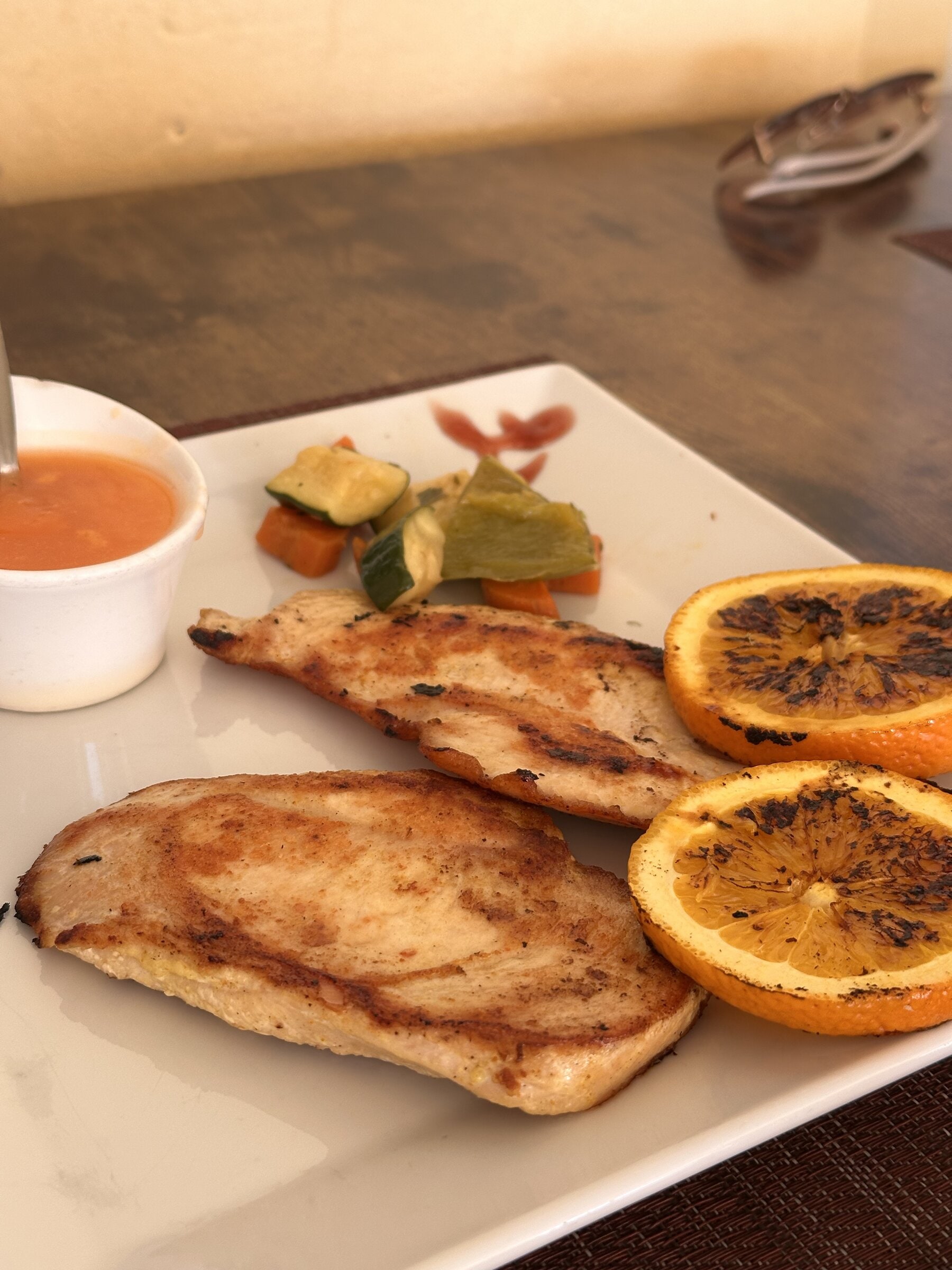 Pechuga de pollo a la plancha con rodajas de naranja asada, verduras salteadas y salsa, en el restaurante Limoncello de Costa Adeje.