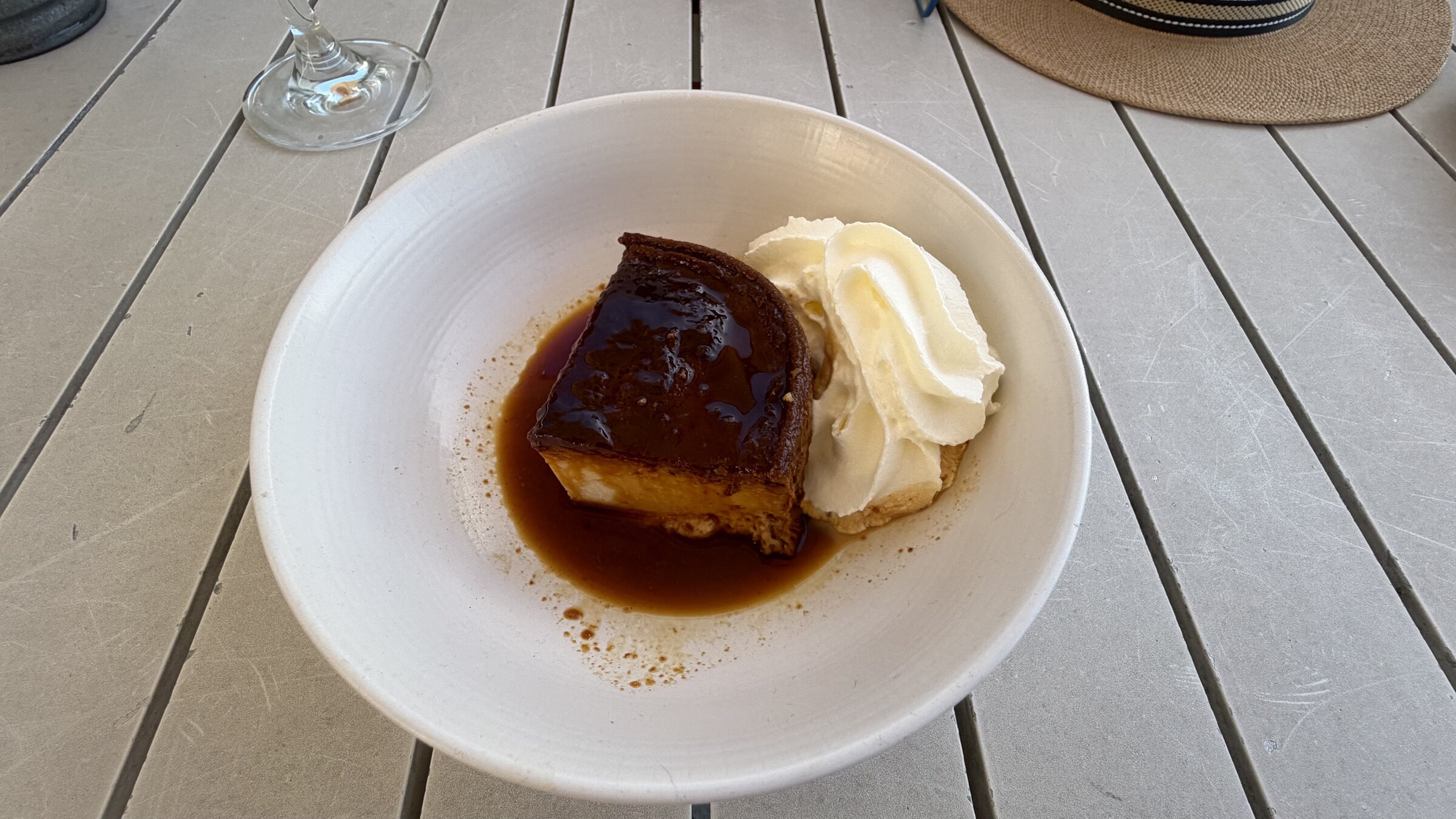 Flan con caramelo y nata montada en un cuenco blanco.