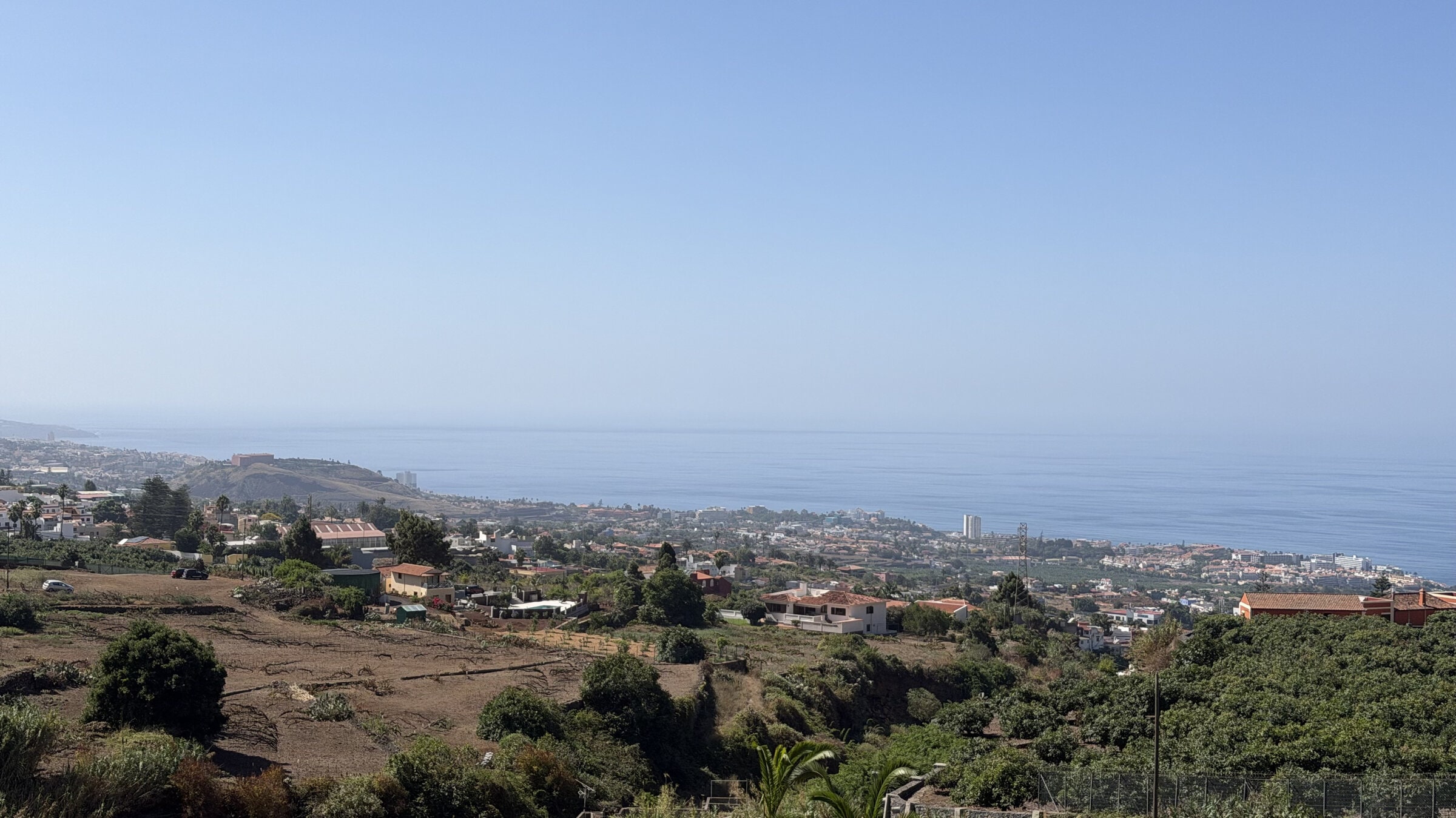Vista desde el Guachinche El Cubano hacia la costa y el mar, con fincas y casas en primer plano.